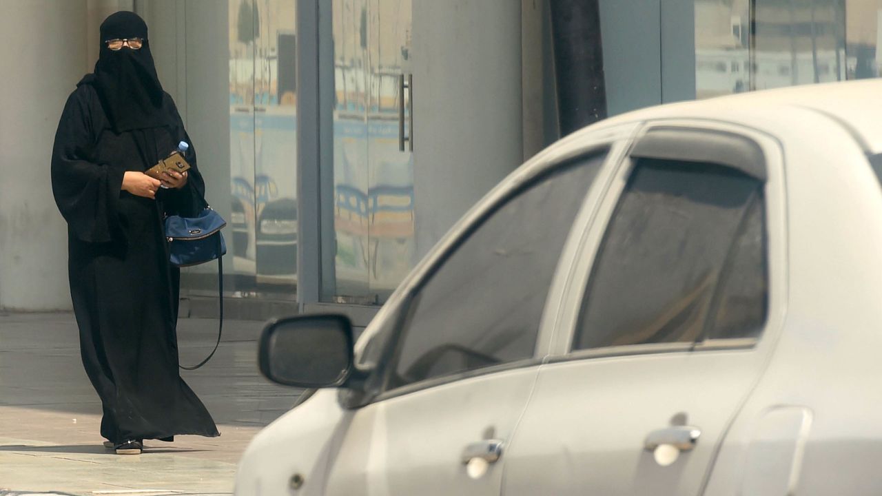 A Saudi woman walks near car down a street in the Saudi capital Riyadh on September 27, 2017.