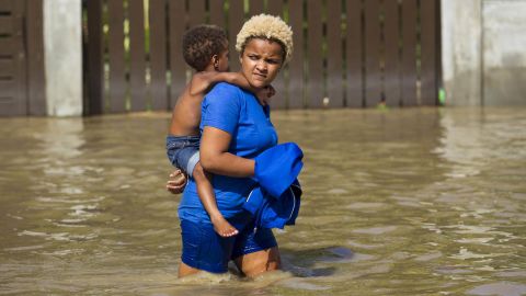 Residents wade through the flooded streets of Arenoso, a town in the northeast of the Dominican Republic, on September 24, 2017.
