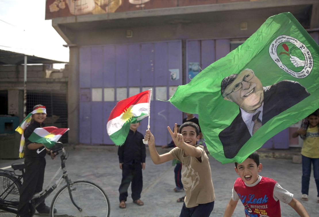Children holding Kurdish flags run through the streets of Kirkuk on Monday.