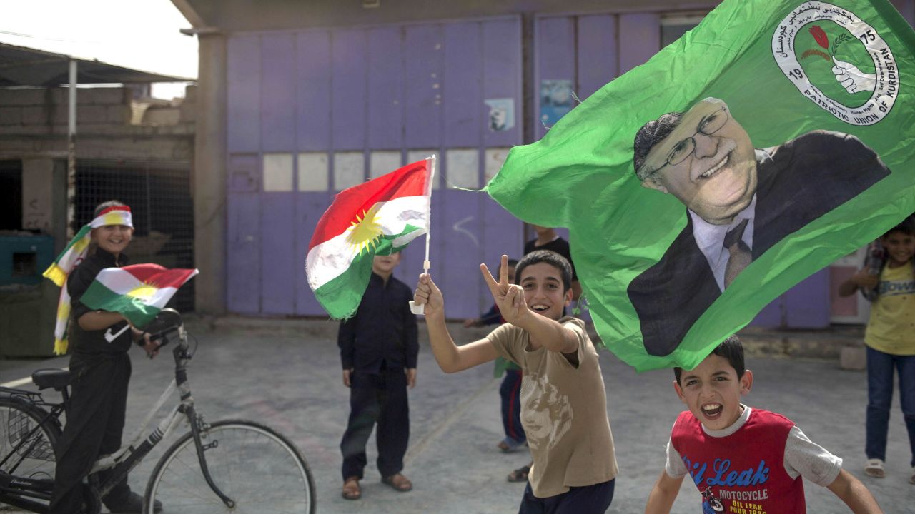 Children holding Kurdish flags run through the streets of Kirkuk on Monday.