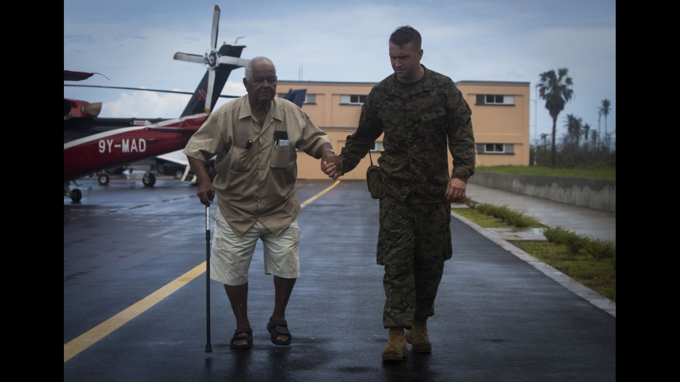 Marine Gunnery Sgt. Philip C. Sackett escorts a US citizen to an evacuation control center at the Douglas-Charles Airport in Dominica on Sunday, September 24. The control center was set up to help people who were stranded on the island after Hurricane Maria.