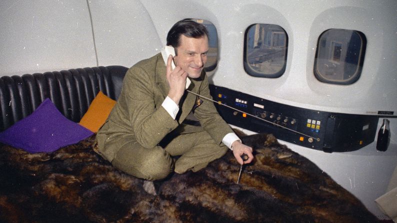 Hefner is seen taking a phone call aboard his private plane in 1970.