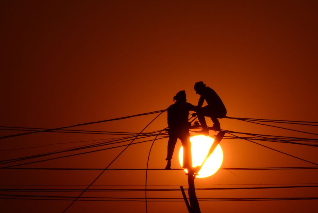 Indian workers adjust electricity cables set up temporarily on the banks of the river Ganga, December 26, 2015. 