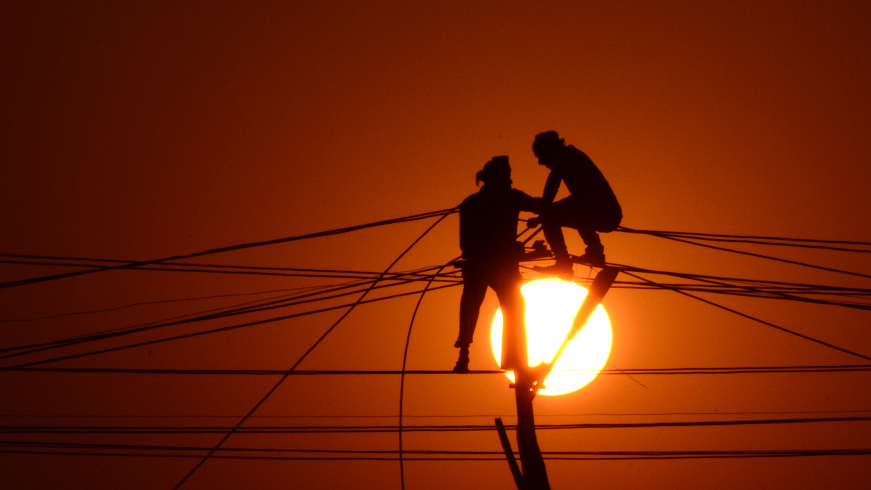Indian workers adjust electricity cables set up temporarily on the banks of the river Ganga, December 26, 2015. 