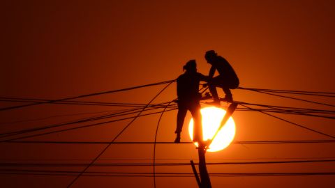 Indian workers adjust electricity cables set up temporarily on the banks of the river Ganga, December 26, 2015.