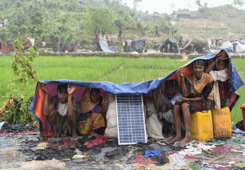 Rohingya refugees take cover from monsoon rains on September 17 in the Balukhali refugee camp in Bangladesh.