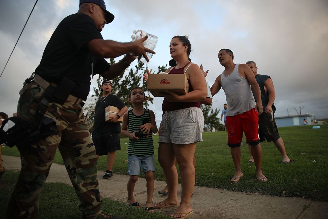 Police Sgt. Nelson Sierra hands out food and water to hurricane survivors Thursday in Toa Baja. 