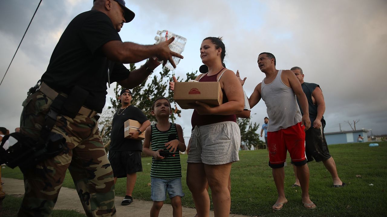 Police Sgt. Nelson Sierra hands out food and water to hurricane survivors Thursday in Toa Baja.