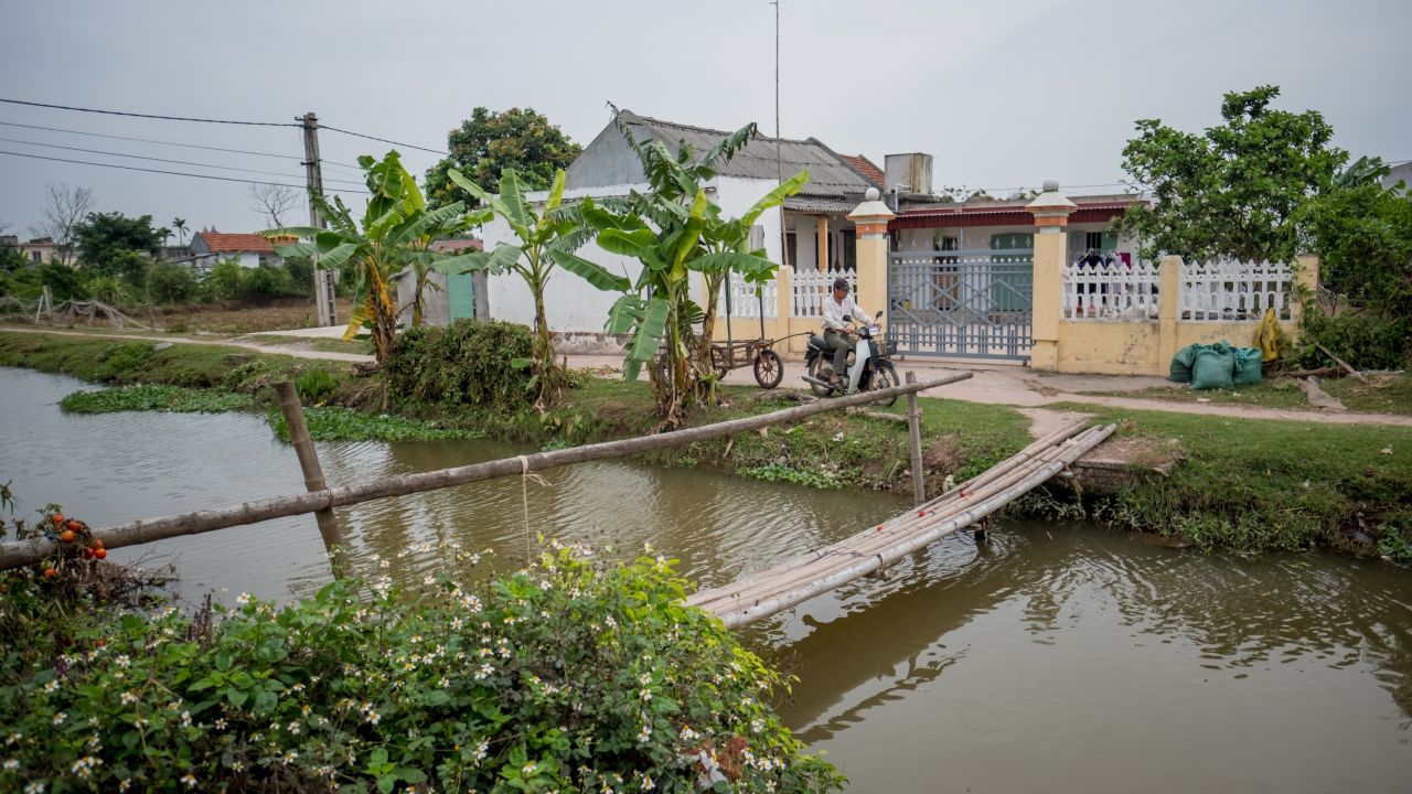 Doan Van Binh, 41, brother of Doan Thi Huong, drives his motorbike-cart in front of to Huong's family home with yellow-painted walls on February 27, 2017 in Nghia Binh, a village 130km from Hanoi, Vietnam.