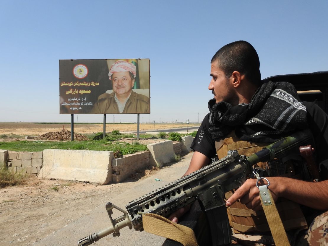 A Peshmerga fighter looks at a billboard of Kurdistan Regional President Masoud Barzani. 