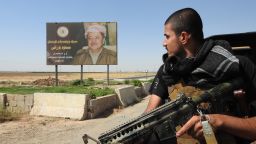 Peshmerga fighter looks at a billboard of Kurdish Regional President Masoud Barzani 