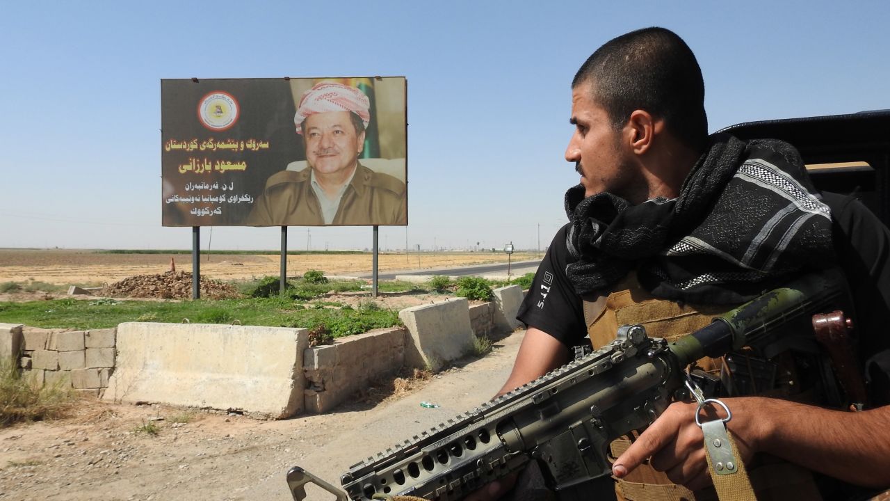 A Peshmerga fighter looks at a billboard of Kurdistan Regional President Masoud Barzani. 