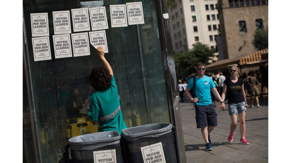A man peels off pro-independence referendum voting posters from a wall on Friday in Barcelona.