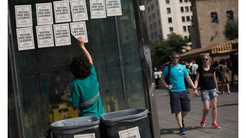 A man peels off pro-independence referendum voting posters from a wall on Friday in Barcelona.