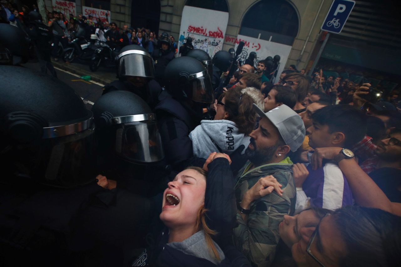 People clash with Spanish National Police outside the Ramon Llull school, designated as a polling station by the Catalan government in Barcelona, Spain, early Sunday, October 1. Catalan pro-referendum supporters vowed to ignore a police ultimatum to leave the schools they are occupying to use in a vote seeking independence from Spain.