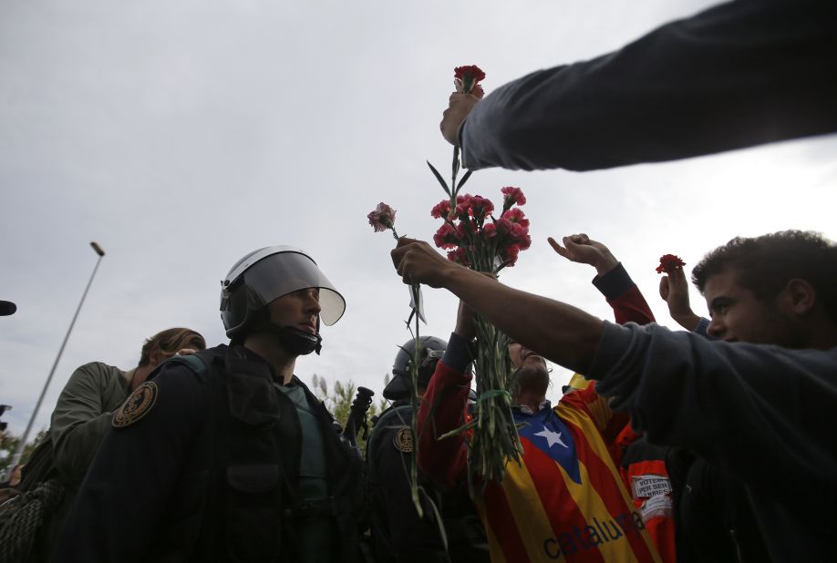 People try to offer flowers to a civil guard at the entrance of a sports center, assigned to be a referendum polling station by the Catalan government in Sant Julia de Ramis, near Girona, Spain, October 1.