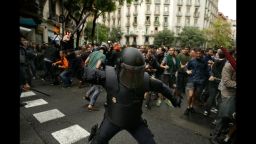 Spanish riot police swings a club against would-be voters near a school assigned to be a polling station by the Catalan government in Barcelona, Spain, Sunday, Oct. 1, 2017. Spanish riot police have forcefully removed a few hundred would-be voters from several polling stations in Barcelona. (AP Photo/Manu Fernandez)