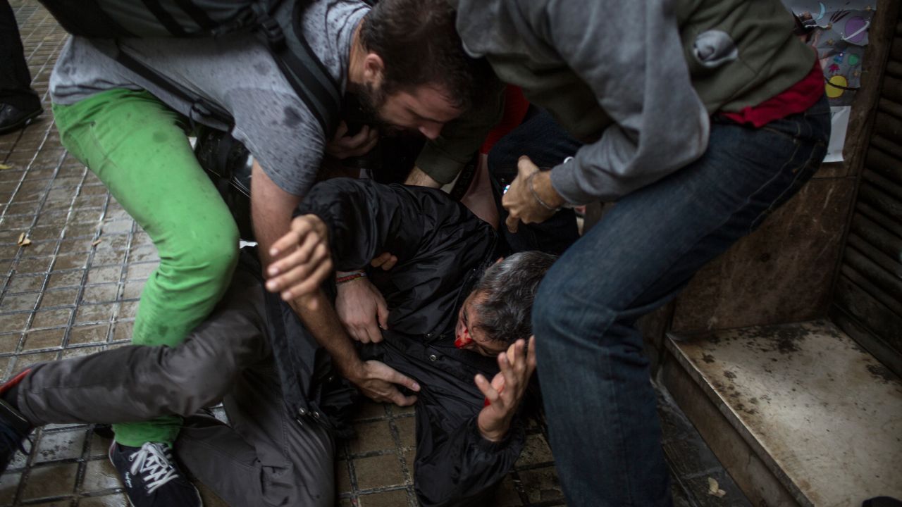 People help a man injured by a rubber bullet fired by Spanish police officers outside the Ramon Llull polling station in Barcelona.