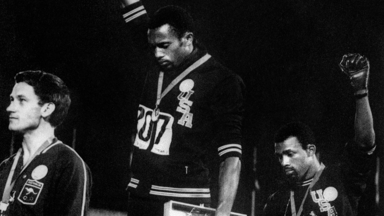 Tommie Smith, center, and John Carlos raise gloved fists during the Olympics in 1968.