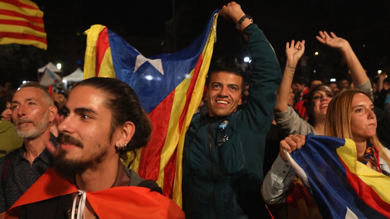People hold Catalan flags as they listen to Catalan President Carles Puigdemont speak as they await the referendum result.