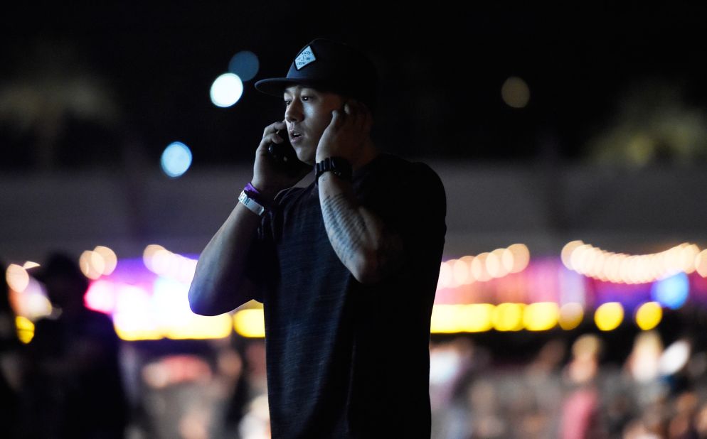 A man makes a phone call as people run from the festival grounds.