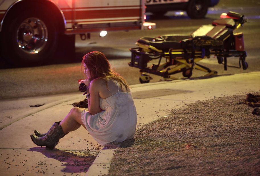 A woman sits on a curb at the scene of the shooting.