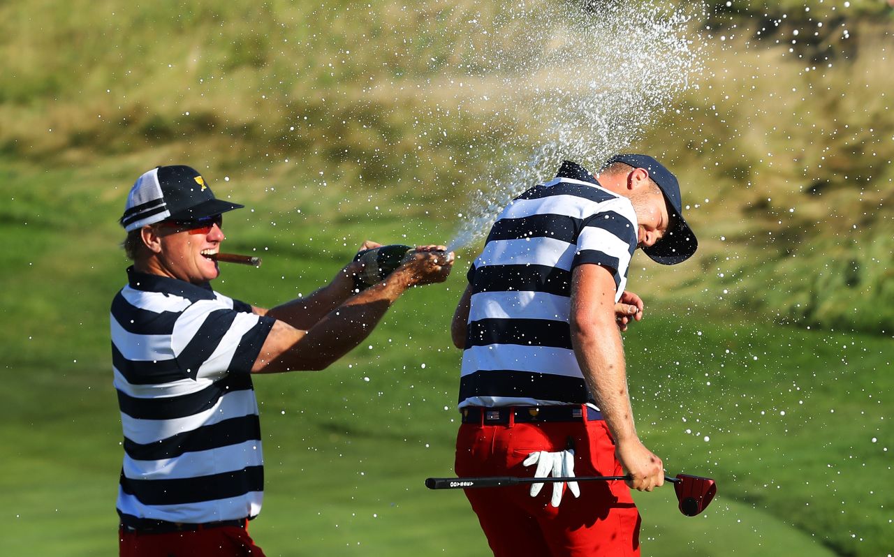 Berger is sprayed with champagne by a cigar-toting Hoffman. 