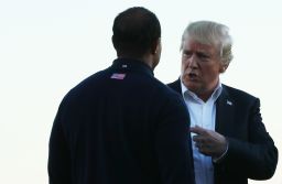 U.S. President Donald Trump talks to Captain's assistant Tiger Woods