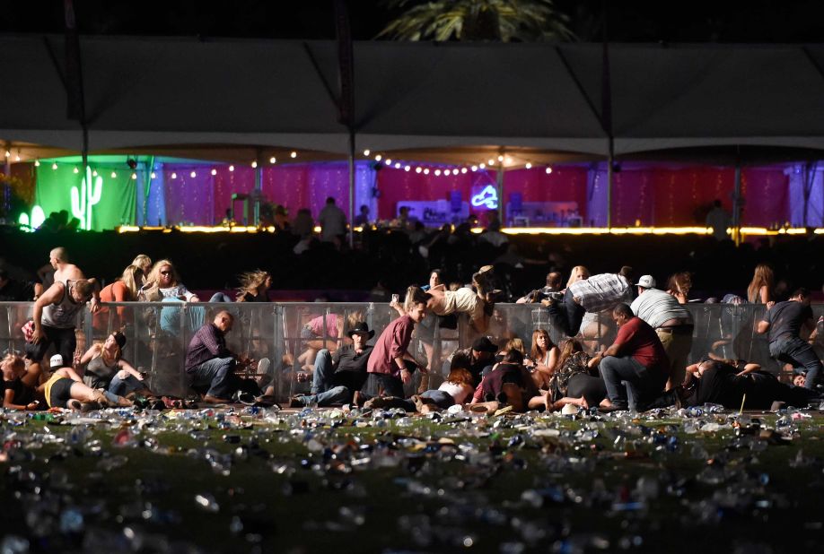 Concertgoers dive over a fence to take cover from gunfire on Sunday night.