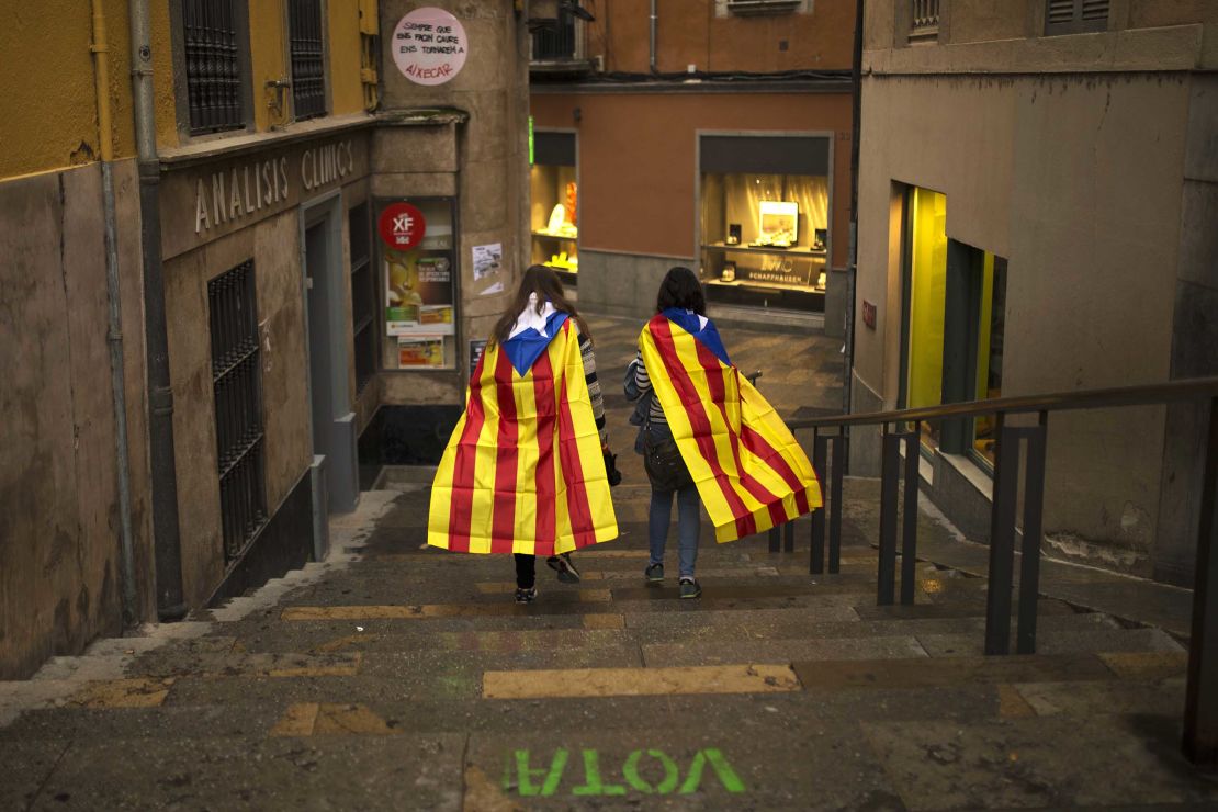 Women walk in the old quarter of Girona, Spain, draped in Catalonia's independence flag.