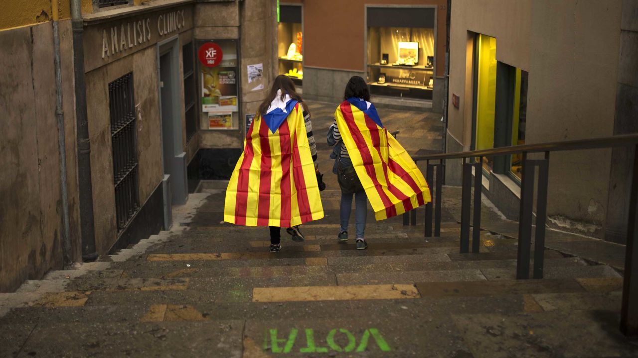 Women walk in the old quarter of Girona, Spain, draped in Catalonia's independence flag.