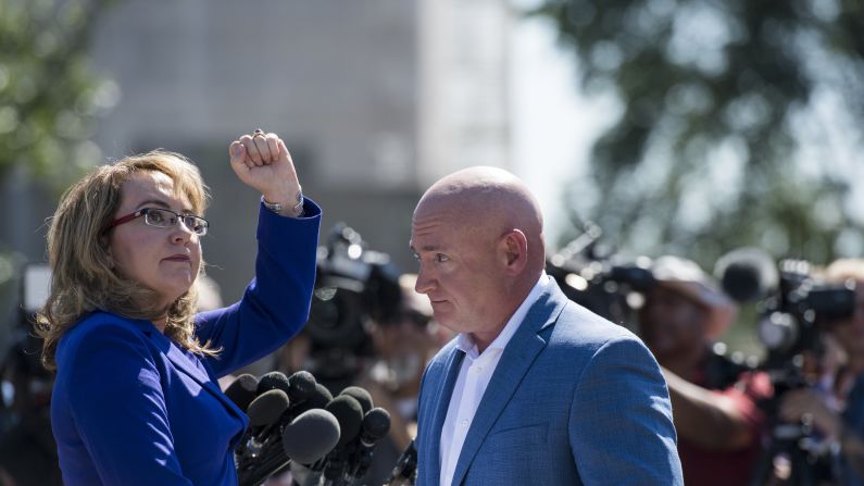 Former US Rep. Gabrielle Giffords -- accompanied by her husband, Mark Kelly -- turns to shake her fist at the Capitol during a news conference on October 2. Giffords, who was shot by a constituent in 2011, has been calling on Congress to do more to address gun violence.