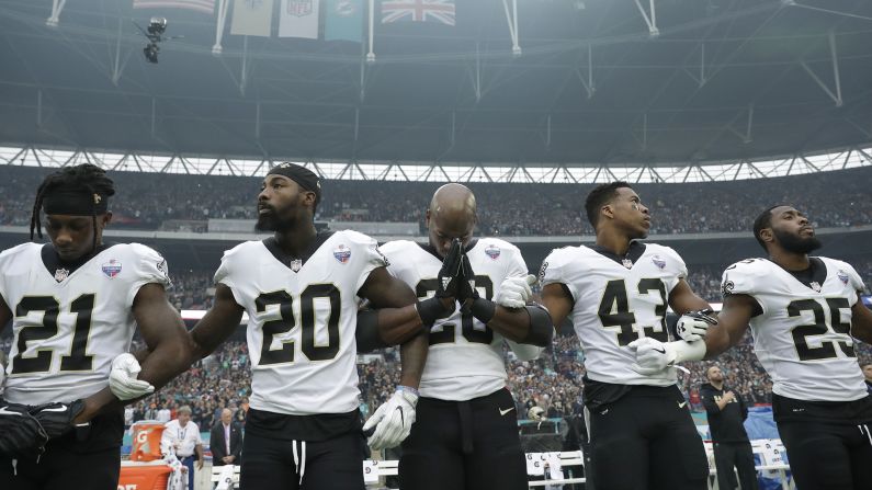 New Orleans running back Adrian Peterson prays as he and teammates lock arms during the National Anthem on Sunday, October 1. The Saints were playing Miami at London's Wembley Stadium.
