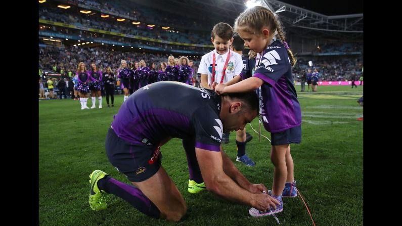 Melbourne captain Cameron Smith ties his daughter's shoelaces after his team won the grand final of the National Rugby League on Sunday, October 1. The Storm defeated North Queensland 34-6 in Sydney.