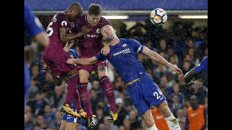 Chelsea's Gary Cahill, right, goes up for a header with Manchester City players Fernandinho and John Stones during a Premier League match in London on Saturday, September 30.
