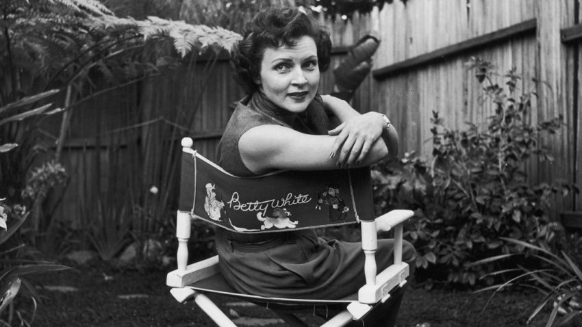 circa 1956:  American actor Betty White sits in a canvas chair with her name written on the back, looking over her shoulder in a backyard garden.  (Photo by Hulton Archive/Getty Images)