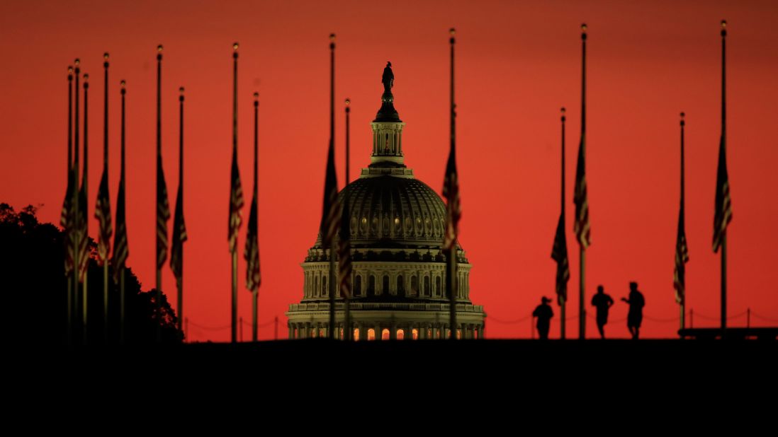 American flags stand at half-staff as the sun rises over Washington on October 3.