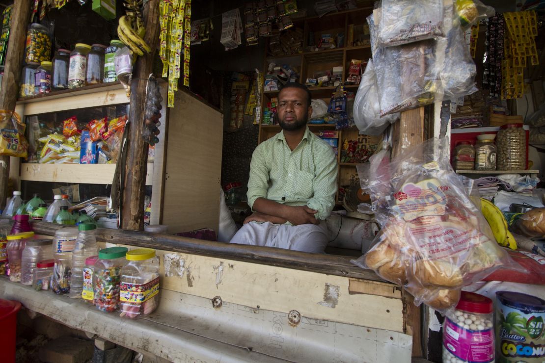 Salimullah, a Rohingya refugee who fled Myanmar in 2003, sits in front of the general store he now owns and operates in the Kanchan Kunj Rohingya settlement in New Delhi, India. 