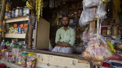 Salimullah, a Rohingya refugee who fled Myanmar in 2003, sits in front of the general store he now owns and operates in the Kanchan Kunj Rohingya settlement in New Delhi, India. 