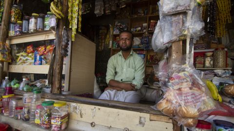 Salimullah, a Rohingya refugee who fled Myanmar in 2003, sits in front of the general store he now owns and operates in the Kanchan Kunj Rohingya settlement in New Delhi, India.