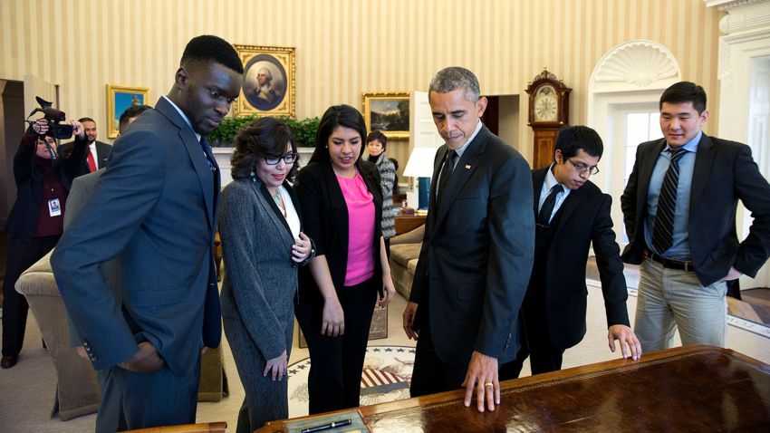President Barack Obama shows the Resolute Desk to a group of DREAMers, following their Oval Office meeting in which they talked about how they have benefited from the Deferred Action for Childhood Arrivals immigration reform program, Feb. 4, 2015. (Official White House Photo by Pete Souza)This official White House photograph is being made available only for publication by news organizations and/or for personal use printing by the subject(s) of the photograph. The photograph may not be manipulated in any way and may not be used in commercial or political materials, advertisements, emails, products, promotions that in any way suggests approval or endorsement of the President, the First Family, or the White House.