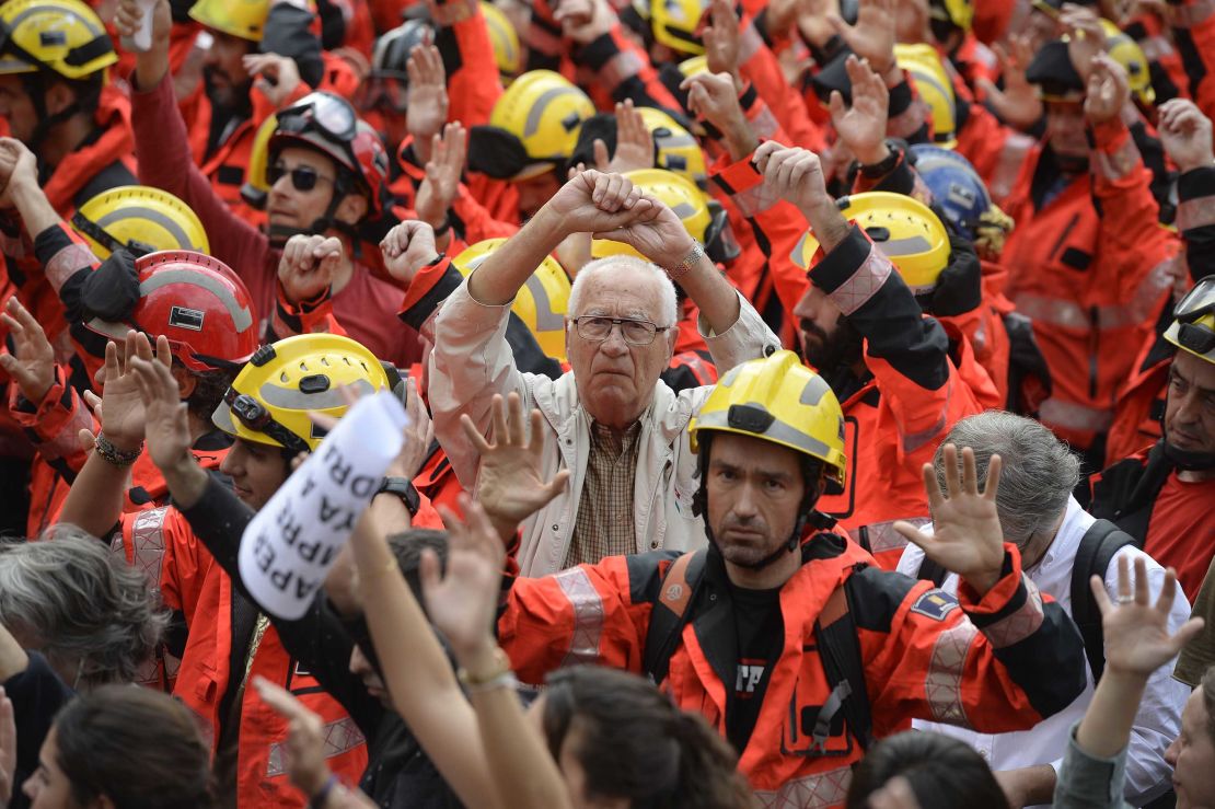 Protesters joined by firefighters raise their hands as they gather during a general strike in Barcelona Tuesday.