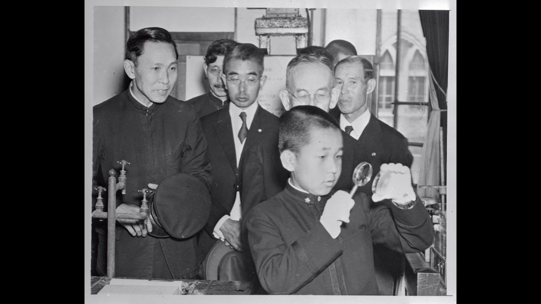 Akihito, 14, uses a magnifying glass at the Peers School in Tokyo. At about the age of 5, Akihito was separated from his parents, in accordance with Japanese custom at the time, and raised and educated by chamberlains and tutors.