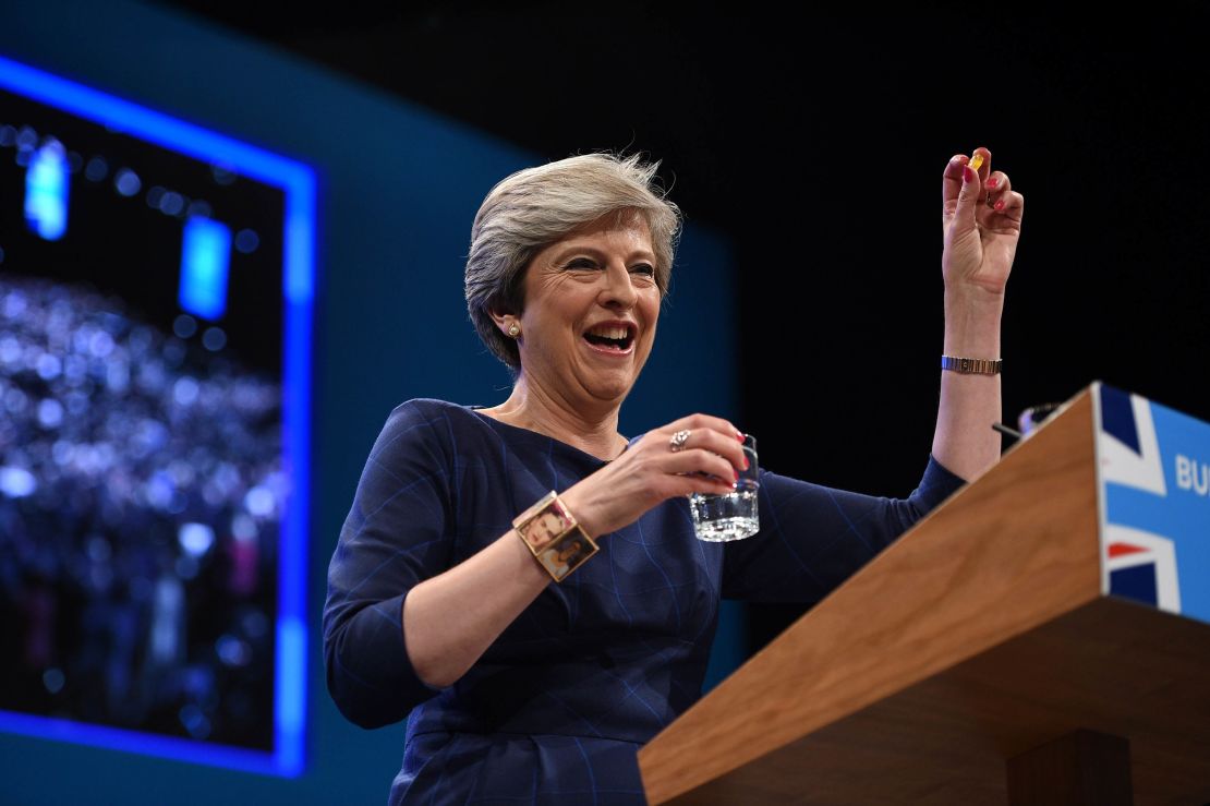 Britain's Prime Minister Theresa May holds up a throat lozenge given to her by Britain's Chancellor  Philip Hammond .