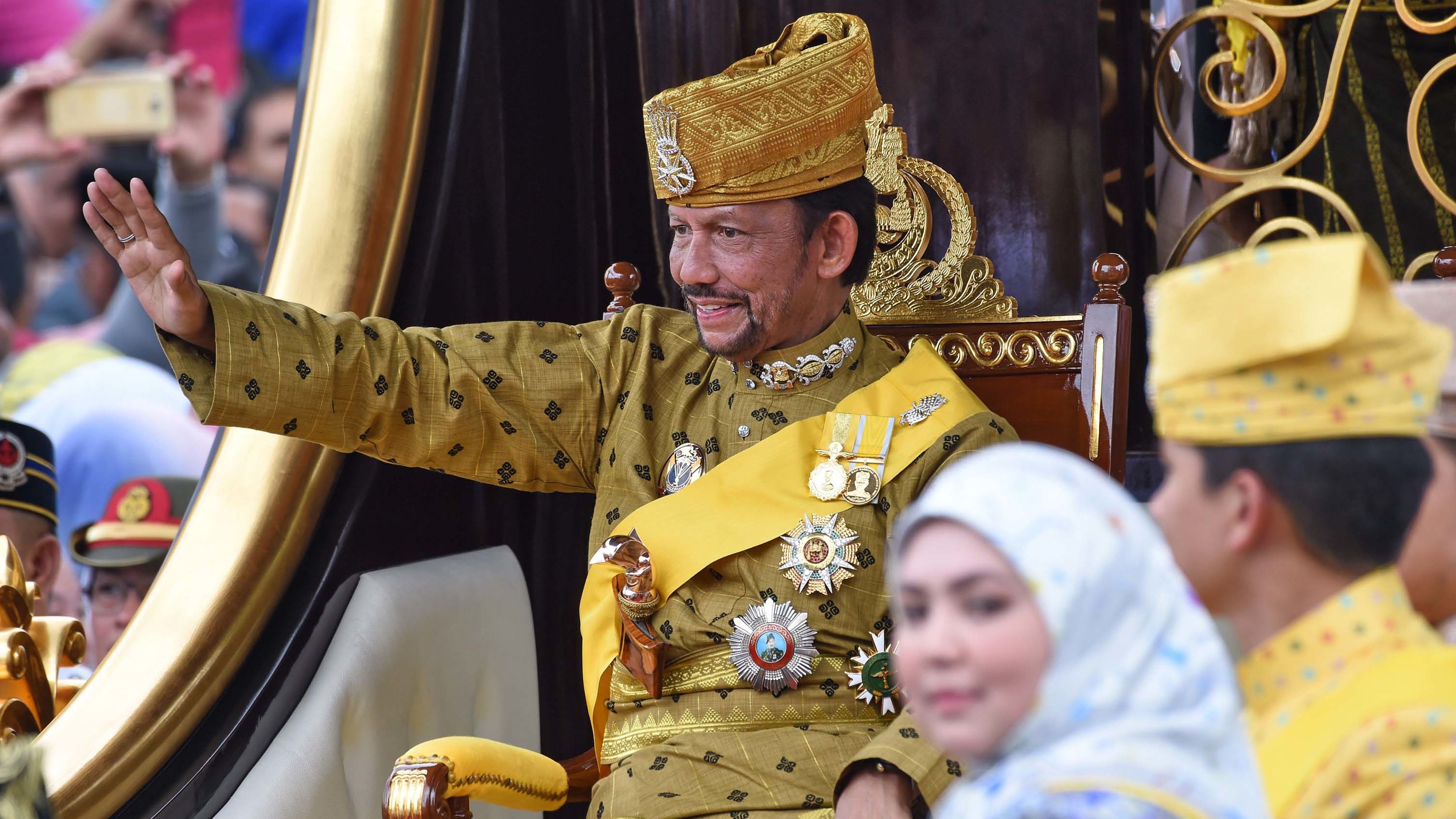 Brunei's Sultan Hassanal Bolkiah waves from the royal chariot during his golden jubilee procession 