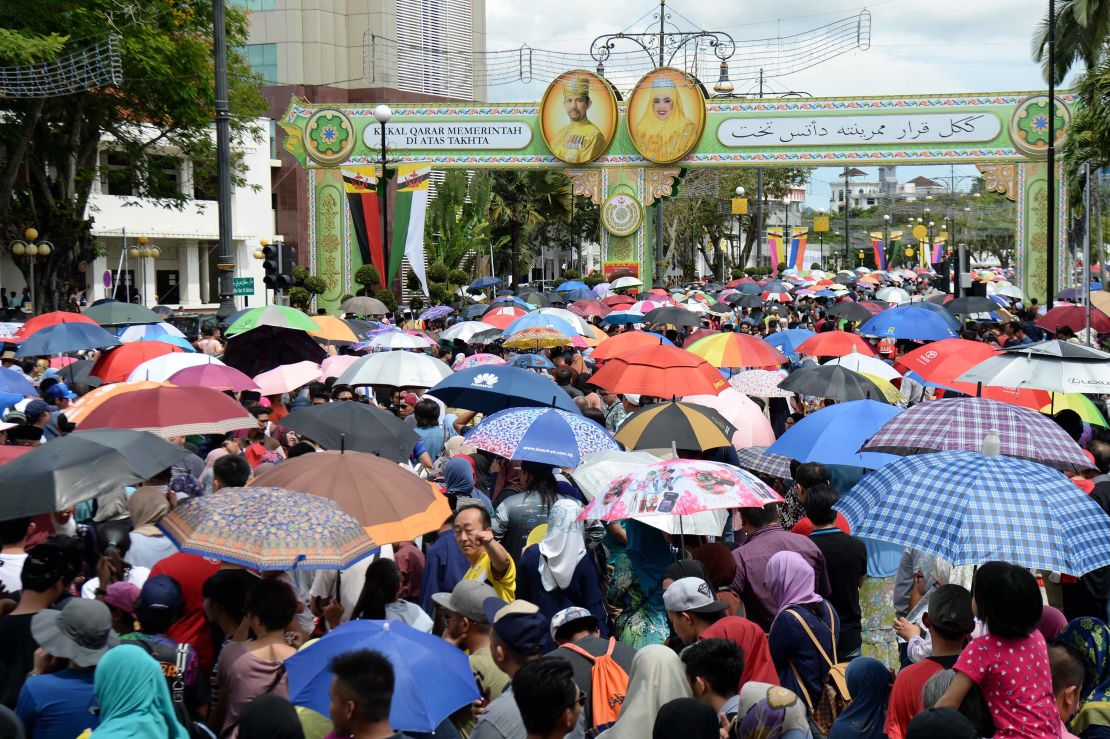 People wait under umbrellas for the royal chariot at jubilee celebrations.