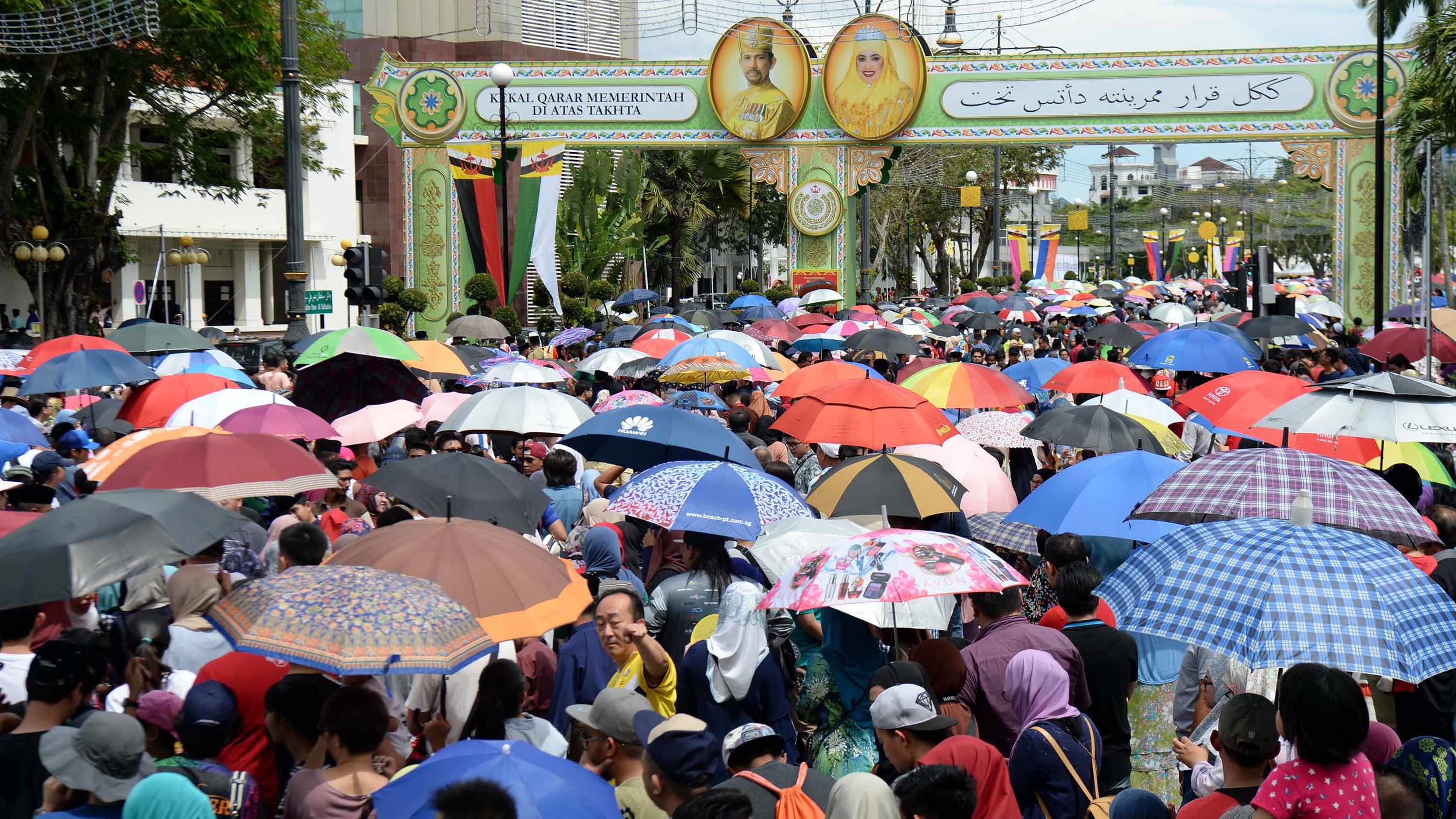 People wait under umbrellas for the royal chariot at jubilee celebrations.