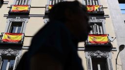 A man walks past a building with Spanish flags hanging from the balconies in Madrid, on September 30, 2017. Thousands of people, many waving red and yellow Spanish flags, rallied in Madrid in favour of Spanish unity today, a day before an banned independence referendum in Catalonia. / AFP PHOTO / GABRIEL BOUYS        (Photo credit should read GABRIEL BOUYS/AFP/Getty Images)