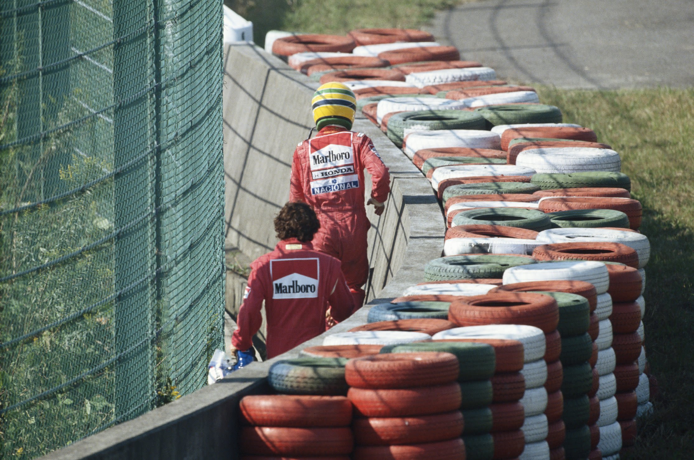 Prost and Senna make their way back to the pit lane on foot after the crash which handed the Brazilian the world title that season.   