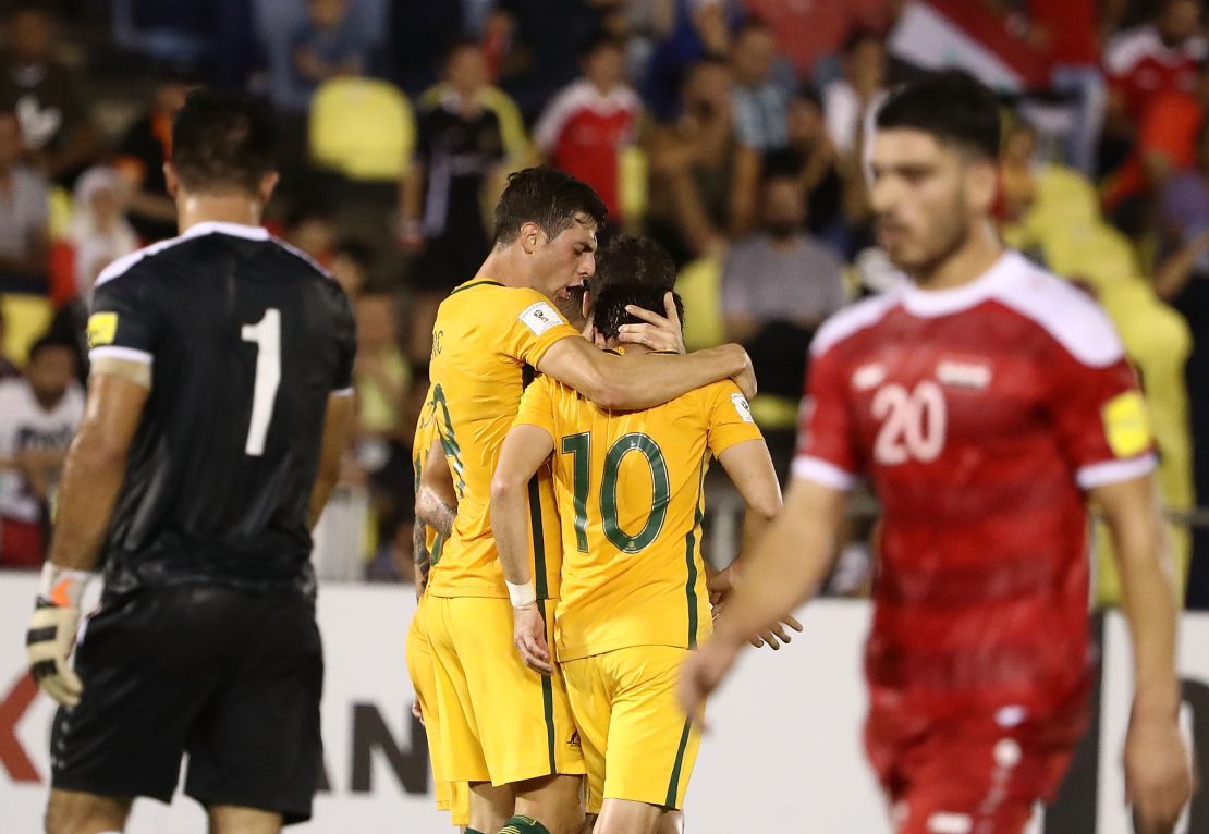 Robbie Kruse celebrates giving Australia the lead, as Syria's players look on dejected.